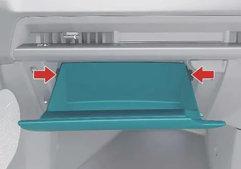 Pressing the sides of the glove box to remove it during cabin filter maintenance on a Kia EV2