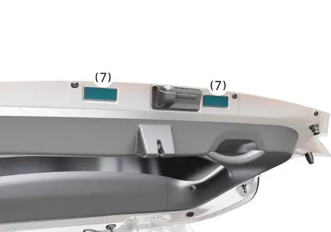 Close-up reference image indicating the exact mounting position of the license plate lamp on the rear bumper of the Kia EV2